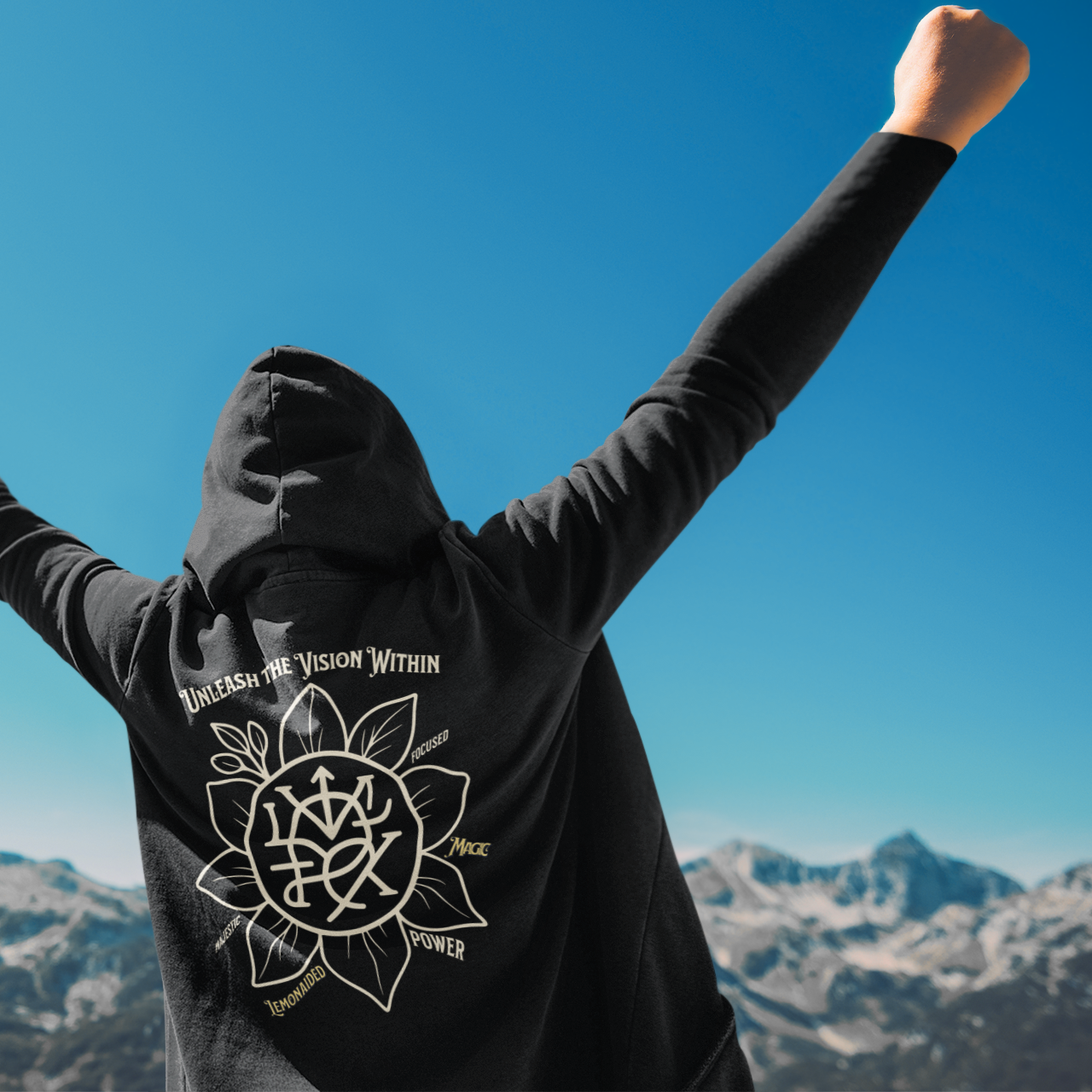 Lifestyle photo of Lemonaided Magic hoodie with hand-drawn personalized sigil — Mercury Loves Osiris, person standing with arms raised against a mountainous background.