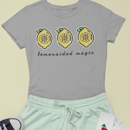 Flat lay of Lemonaided Magic custom sigil T-shirt — personalized affirmation shirt on lemon background Gray t-shirt with lemon design and text, mint shorts, white socks with cherry design, and black sneakers on a light yellow background.